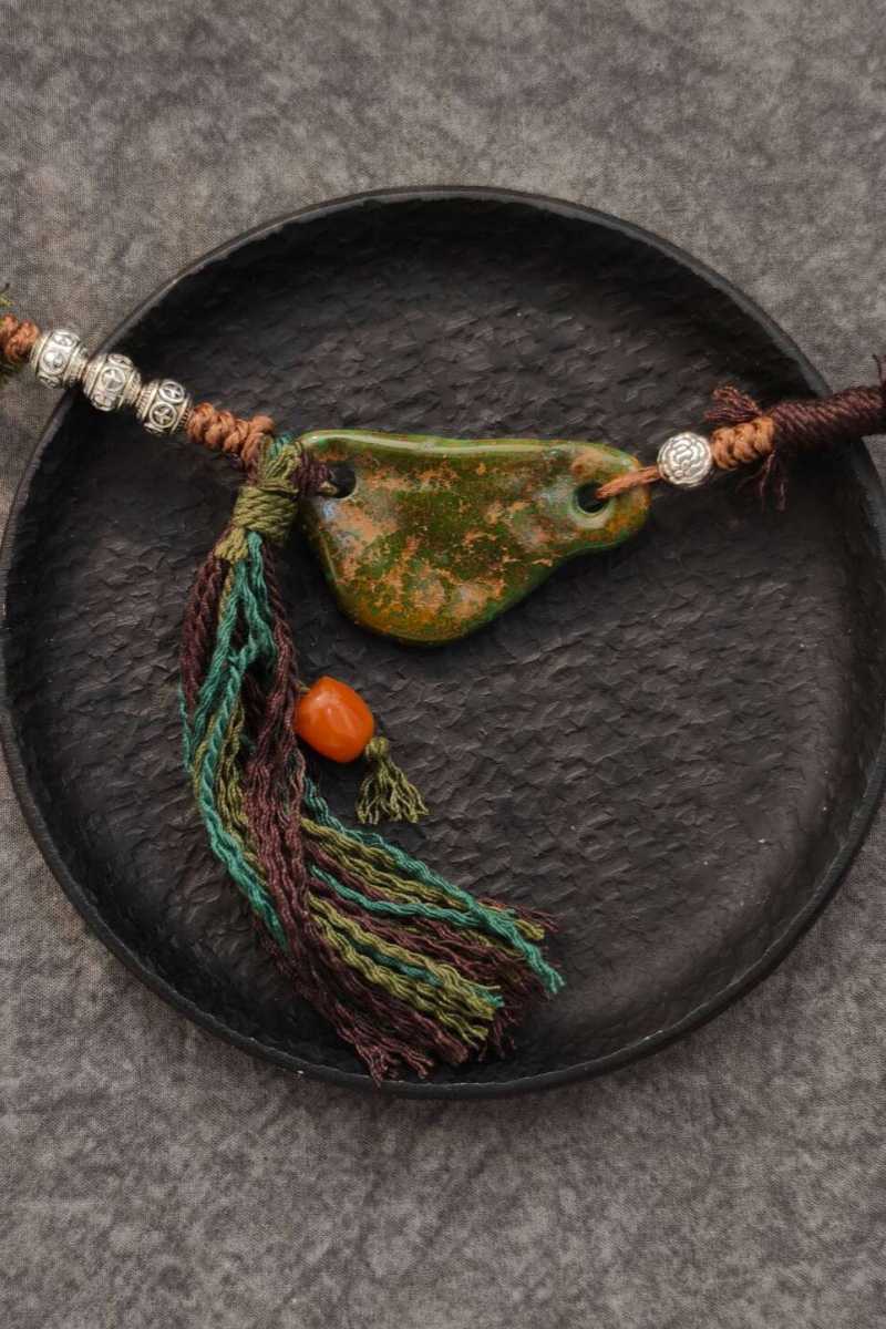 "Sospeso" | Collana con Scaglia di Turchese Orizzontale, Corda Tibetana Intrecciata, Grani d'Argento Incisi e Nappa con Corallo - Gioiello Artigianale dal Movimento Eolico